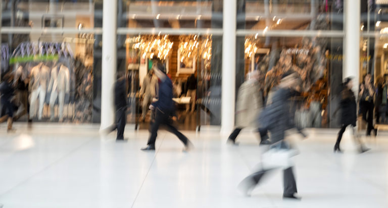 Shopper walking in front of shop window at dusk