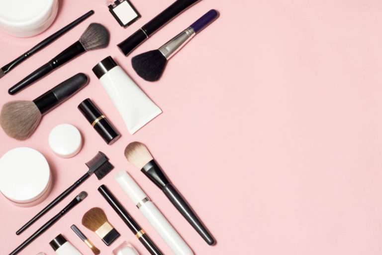 Concept of a cosmetic tubes and cream containers top view on pink background