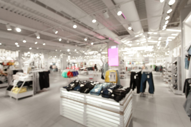 Sale and seasonal change of collection. Blurred View of fashionable clothing store in shopping center. Led lighting on the ceiling. Fire system and air conditioning system in retail shop